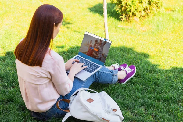 有吸引力的妇女使用笔记本电脑与加载 Couchsurfing 页面在公园 — 图库照片