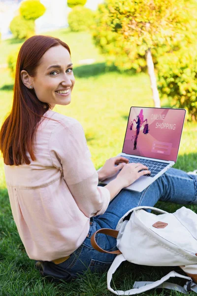 微笑有吸引力的妇女使用笔记本电脑与在线购物设备在公园和看相机 — 图库照片