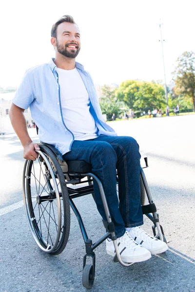 英俊的微笑的人使用轮椅在街上和查找 — 图库照片