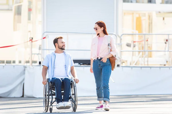 英俊的男朋友在轮椅和女朋友走 看着对方在街上 — 免费的图库照片