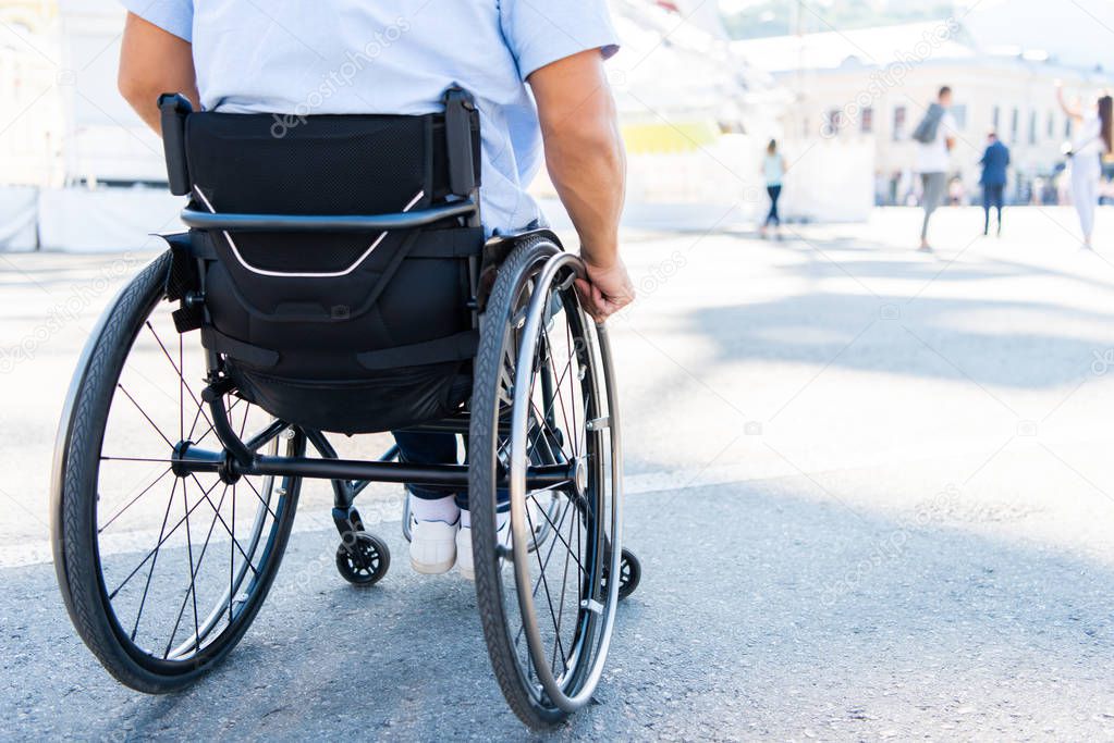 cropped image of man using wheelchair on street