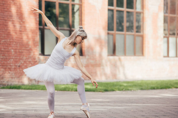 attractive young ballerina in tutu skirt dancing on urban street    