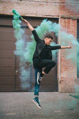 Genç erkek Çağdaş dansçı yeşil duman kentsel Caddesi üzerinde atlama