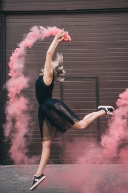 pembe duman içinde sokakta genç kadın dansçı yan görünüm 