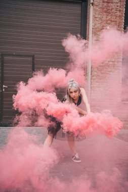 pembe duman içinde dans ve kameraya Caddesi üzerinde seyir çekici genç kadın 