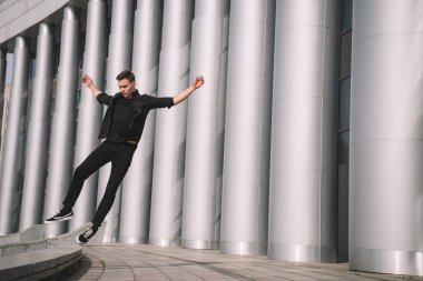 yakışıklı genç adam sokakta dans atlama siyah giysili 