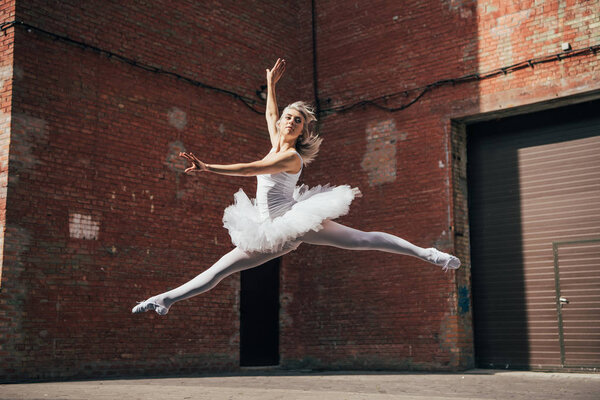 beautiful young ballerina jumping and dancing on urban street 