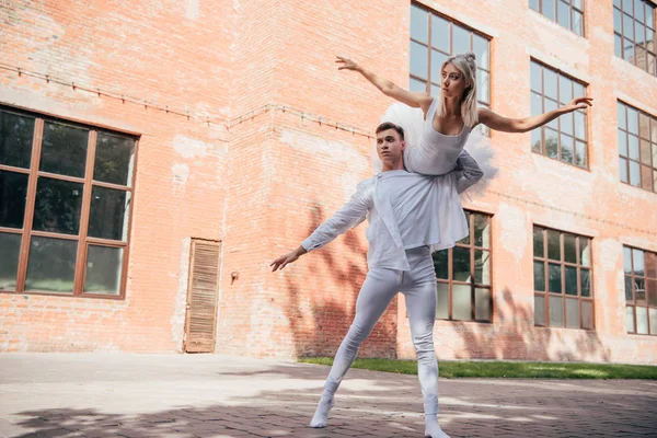 都市通りの上で踊って白衣の若いバレエ ダンサーの低角度のビュー  — 無料ストックフォト