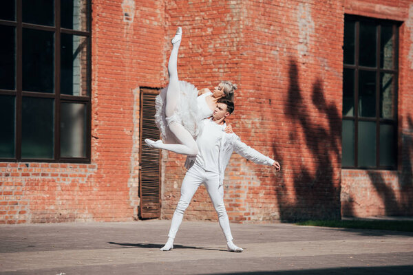 пара молодых артистов балета, танцующих на городской улице
