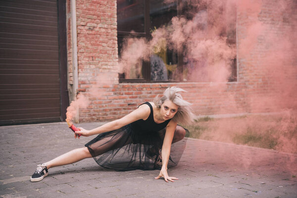 beautiful young female dancer in pink smoke on street