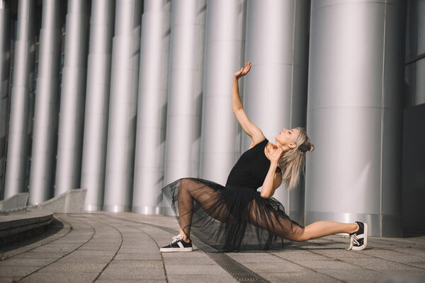attractive young ballerina in black skirt dancing on street 