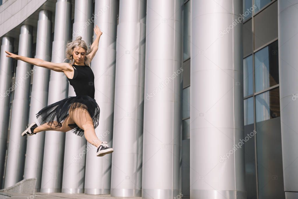 low angle view of young ballerina jumping and dancing on street 