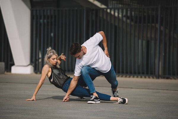 young man and woman dancing on urban city street  