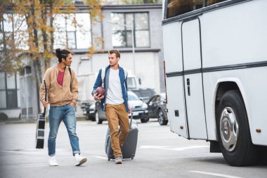 Yakındaki otobüs Street yürüyüş karışık yarış erkek arkadaşı ise seyahat çantası taşıyan rugby topu ile yetişkin adam