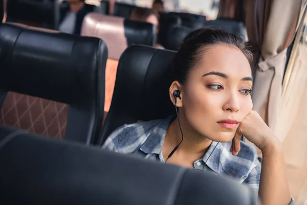 无聊的亚洲妇女在旅途中的耳机听音乐在旅行巴士 — 图库照片