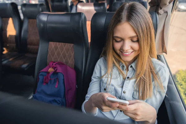 Szczęśliwa Młoda Kobieta Przy Użyciu Smartfona Siedząc Podróż Autobusem — Zdjęcie stockowe
