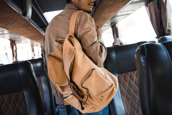 partial view of young male tourist with backpack in travel bus