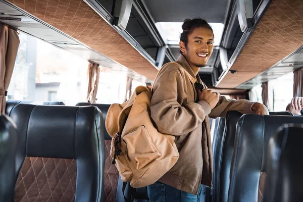 バックパック旅行バスでカメラ目線で笑顔の多民族男性の観光客 — ストック写真