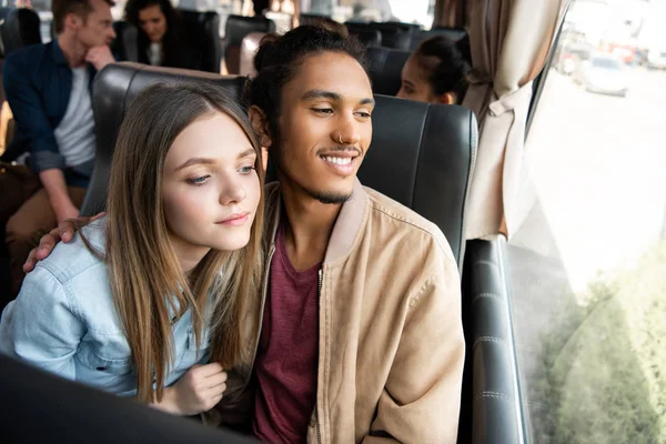 Feliz Casal Interracial Olhando Para Janela Durante Viagem Ônibus Viagem — Fotografia de Stock