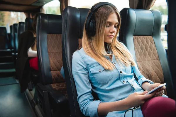 音楽を聴くと バスで旅行中にスマート フォンを使用してヘッドフォンで若い女性旅行者 — ストック写真