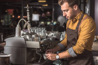 handsome young barista preparing coffee with coffee machine in cafe clipart