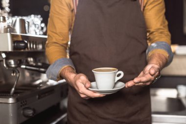 barista önlük taze yapılmış kahve tutarak atış kırpılmış