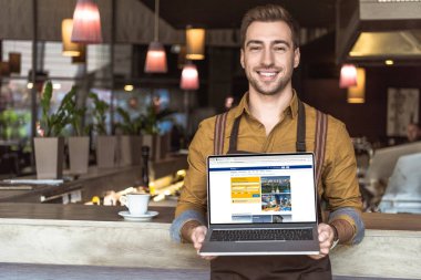 yakışıklı genç garson rezervasyon web sitesi ile dizüstü bilgisayar ekranında kafede holding