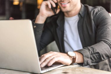 laptop ile çalışma ve kafede telefonla konuşurken gülümseyen genç Freelancer kırpılmış atış
