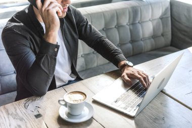 laptop ile çalışma ve kafede telefonla konuşurken genç Freelancer kırpılmış atış