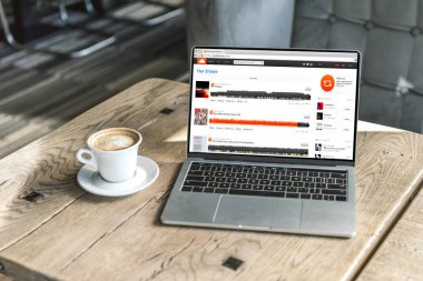 cup of coffee and laptop with soundcloud website on screen on rustic wooden table at cafe clipart