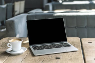 fincan kahve ve kafede rustik ahşap masa boş ekran ile dizüstü bilgisayar