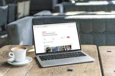 fincan kahve ve airbnb Web sitesinde kafede rustik ahşap masa üstünde perde ile dizüstü bilgisayar
