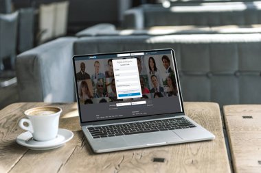 fincan kahve ve LinkedIn Web sitesinde kafede rustik ahşap masa üstünde perde ile dizüstü bilgisayar