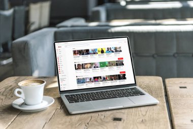 fincan kahve ve youtube Web sitesinde kafede rustik ahşap masa üstünde perde ile dizüstü bilgisayar
