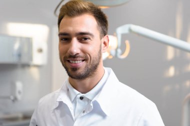 Beyaz önlük kamera Office bakarak genç doktor gülümseyen yakın çekim çekim