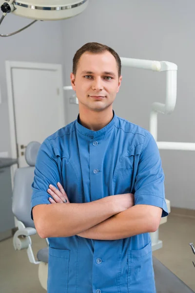 Όμορφος Νεαρός Οδοντίατρος Σταυρωμένα Χέρια Βλέπουν Φωτογραφική Μηχανή Στο Γραφείο — Φωτογραφία Αρχείου