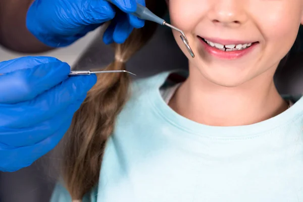 Обрезанный Снимок Стоматолога Инструментами Осматривающими Зубы Улыбающегося Ребенка — стоковое фото
