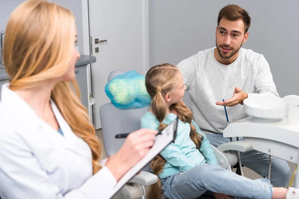 女牙医与剪贴板说话的小孩和她的父亲 — 图库照片