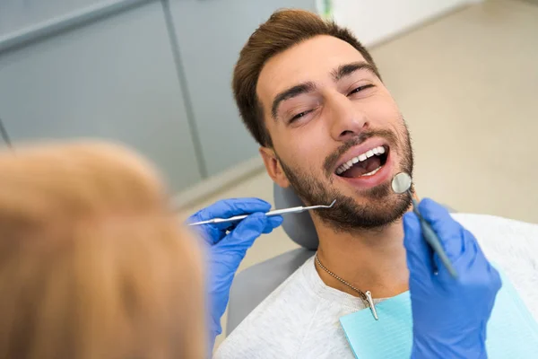 Обрезанный Снимок Женщины Стоматолога Осматривающей Зубы Красивого Счастливого Клиента — стоковое фото