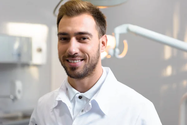 Gros Plan Jeune Dentiste Souriant Manteau Blanc Regardant Caméra Bureau — Photo