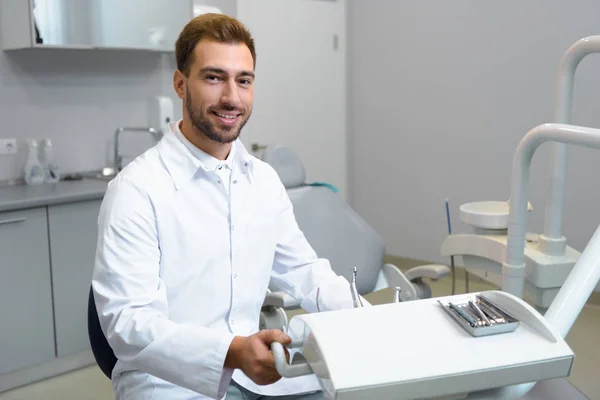 Sonriente Joven Dentista Abrigo Blanco Mirando Cámara Oficina —  Fotos de Stock