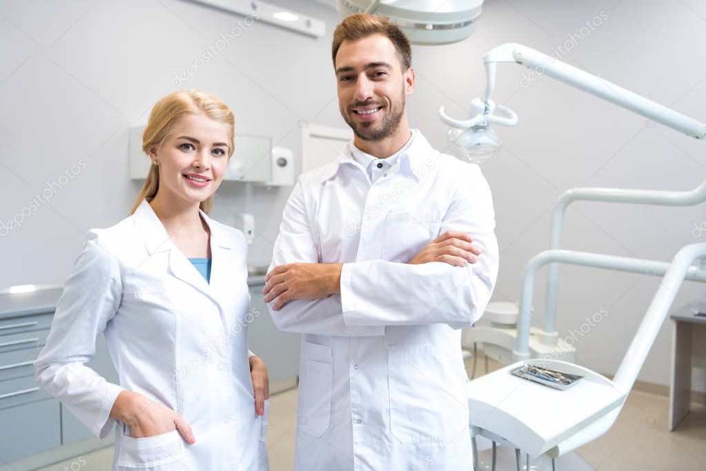 young male and female dentists looking at camera in dental office