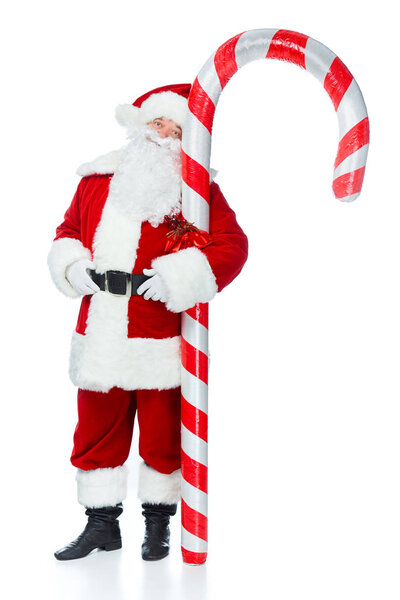 bearded santa claus standing with big christmas candy cane isolated on white