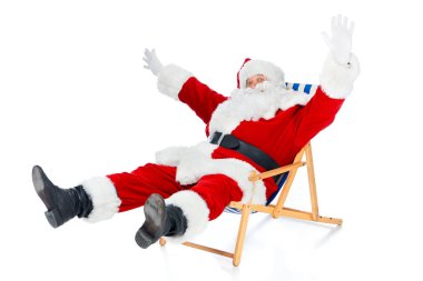 heyecanlı Noel Baba el hareketi ve beyaz plaj sandalye üzerinde oturan