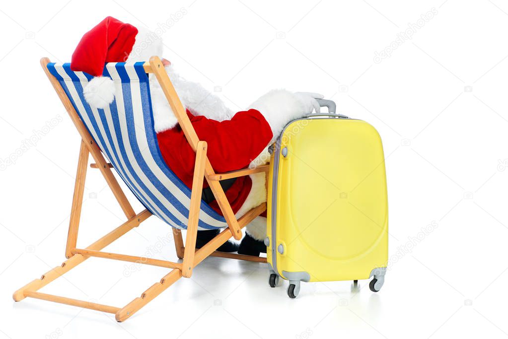 back view of santa claus resting in beach chair with travel bag on white
