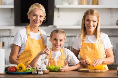 Anne ve granmother birlikte yemek yaparken kameraya gülümseyen güzel mutlu çocuk
