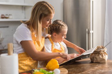 Anne ve kızı kitabı okuma ve birlikte yemek önlük içinde
