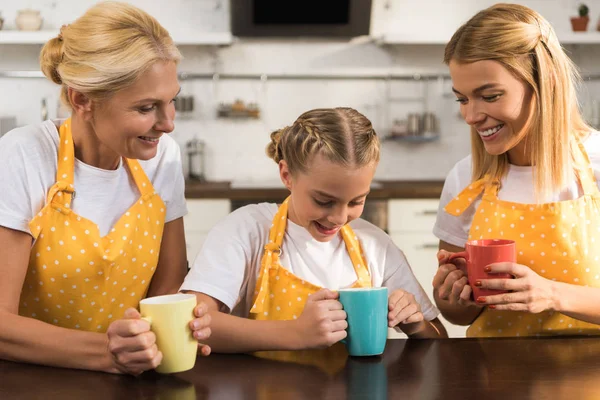 Happy Family Three Generations Aprons Holding Colorful Mugs Kitchen — Stock Photo, Image