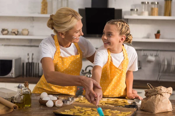 Feliz Abuela Nieta Delantales Sonriéndose Mientras Preparan Galletas Juntos — Foto de Stock