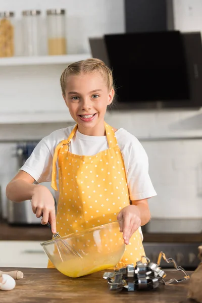 Adorable Happy Child Apron Whisking Eggs Smiling Camera Kitchen — Free Stock Photo